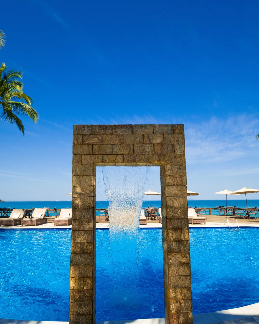 Piscina com cascata de pedra e vista para o mar